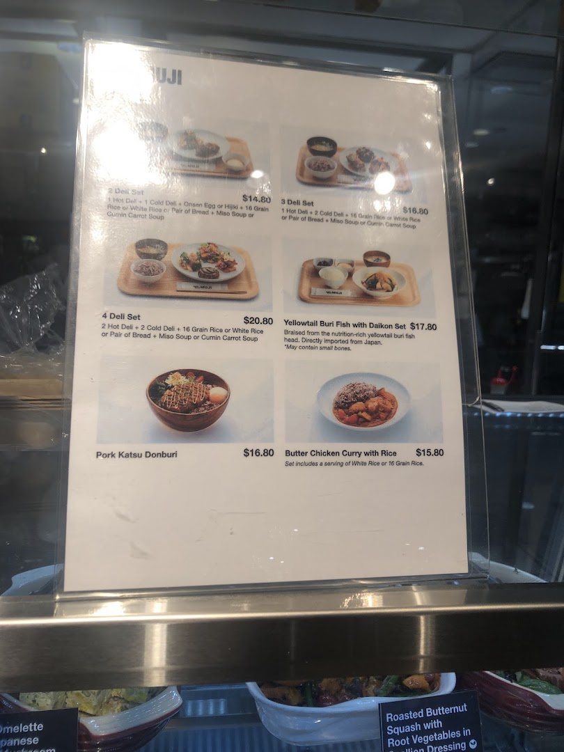 A detailed menu board displaying various deli sets and main dishes with prices at CafèMeal.