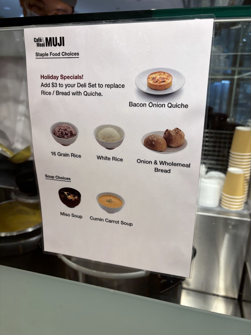 A menu display at CafèMeal MUJI showcasing staple food choices, soups, and a quiche special.