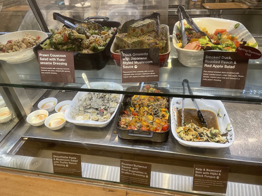 A vibrant display case showcasing a variety of fresh and healthy deli-style dishes at CafèMeal.