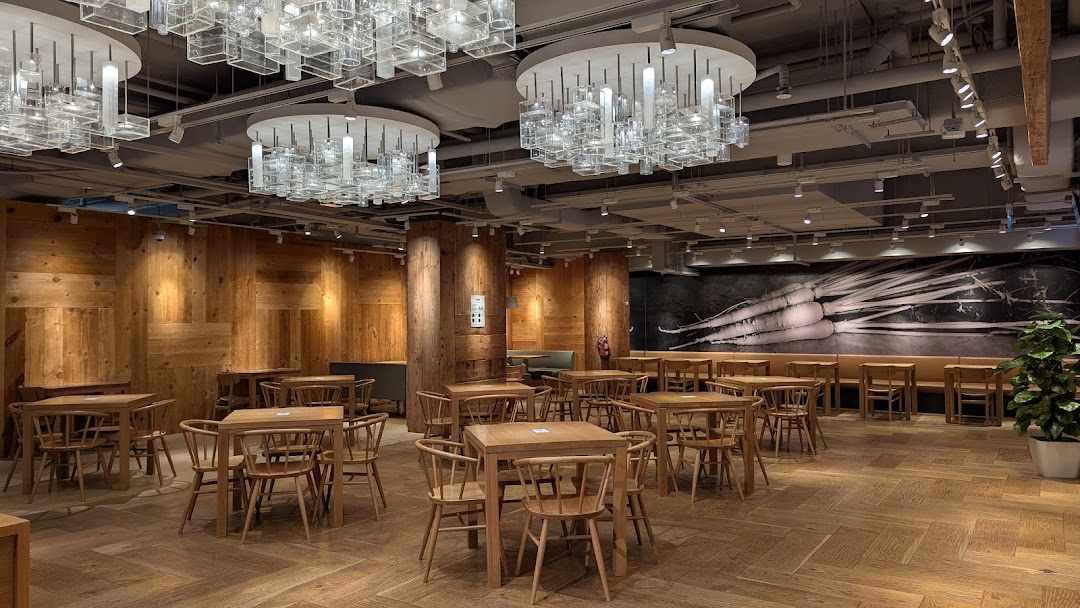 Spacious cafe interior with wooden furniture, unique lighting, and a large root vegetable mural.