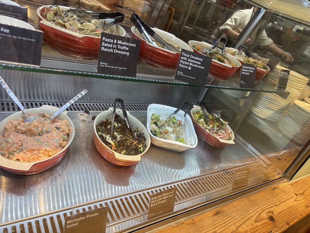 A vibrant display of fresh salads and prepared dishes in a refrigerated counter at CafèMeal.
