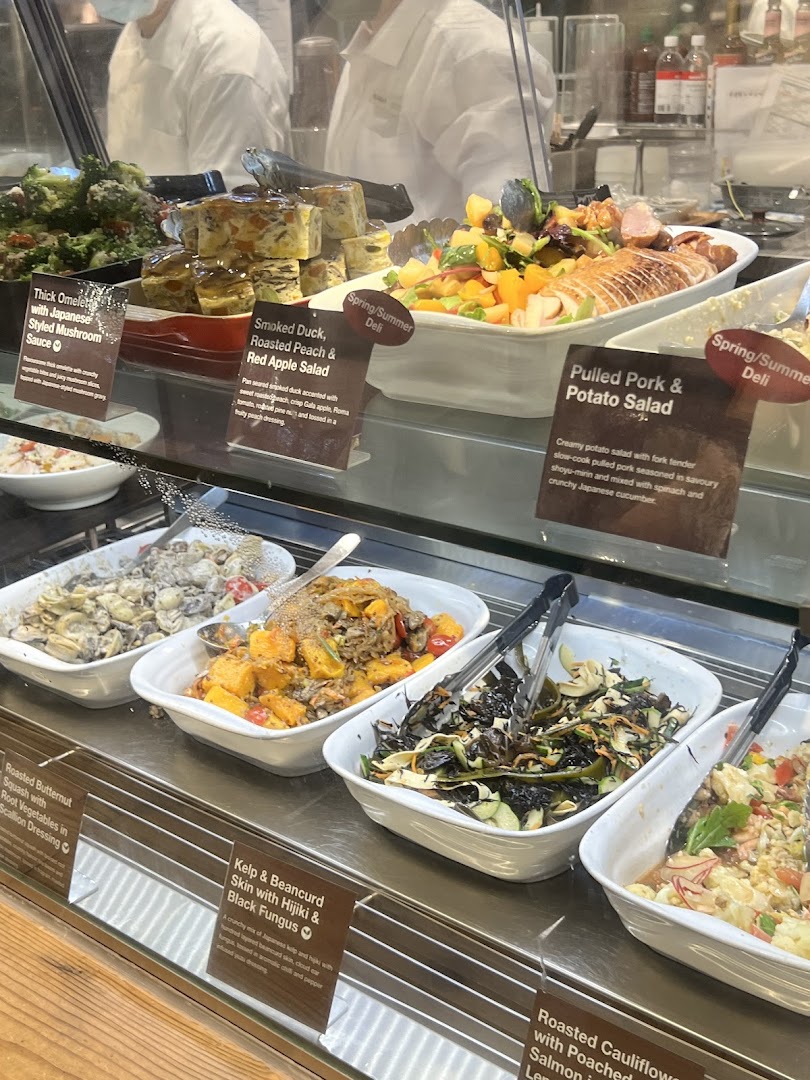A vibrant display of fresh deli items and salads, including omelets, duck salad, and various vegetable dishes.