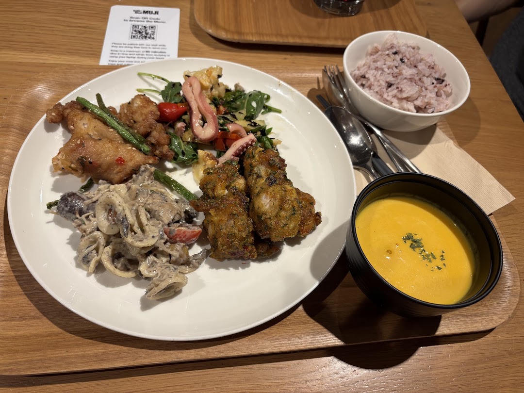 A delicious meal set featuring fried chicken, pasta, salad, rice, and soup on a wooden tray.