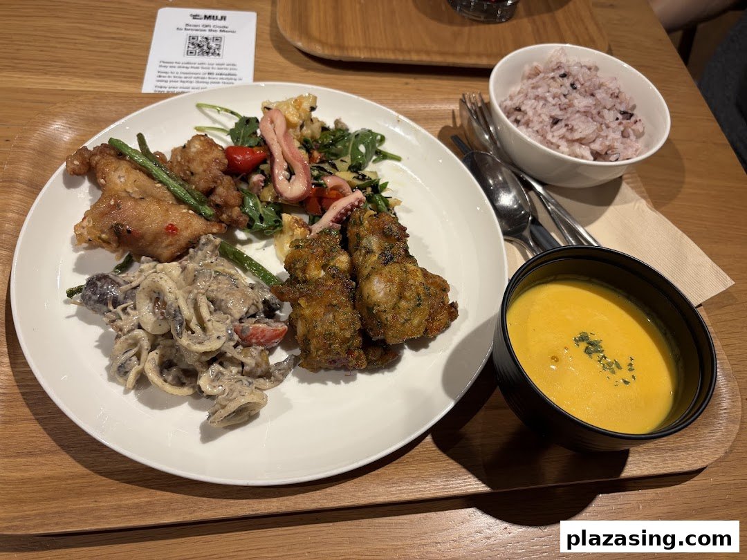 A delicious meal set featuring fried chicken, pasta, salad, rice, and soup on a wooden tray.
