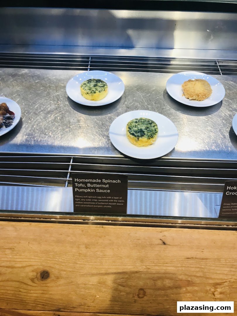 Delicious spinach tofu and other dishes displayed in a modern food counter at CafèMeal.