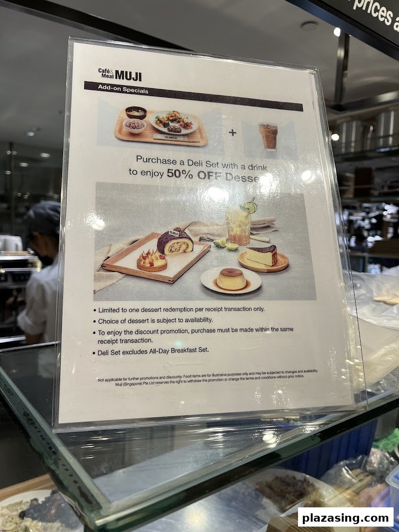 A promotional sign at Cafe&Meal MUJI showcasing a 50% off dessert offer with a deli set purchase.