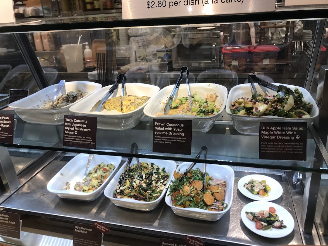 A display case showcasing various fresh salads and prepared dishes at CafèMeal.