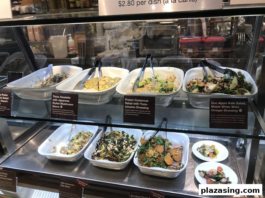 A display case showcasing various fresh salads and prepared dishes at CafèMeal.