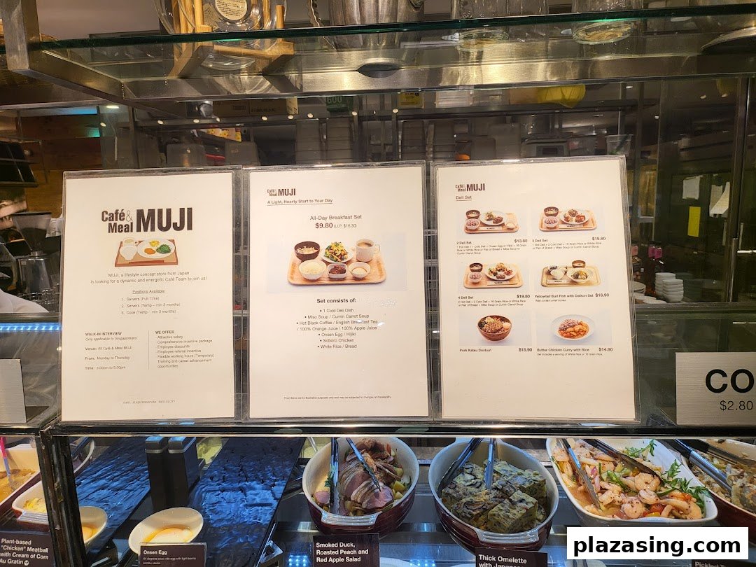 A display case showcasing various deli items and menu boards for breakfast and deli sets at Cafè & Meal MUJI.