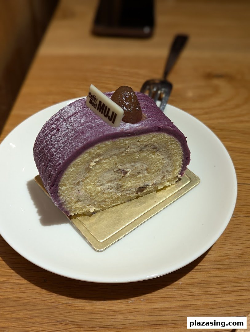A delicious slice of purple sweet potato roll cake with a Café & Meal MUJI tag on a white plate.