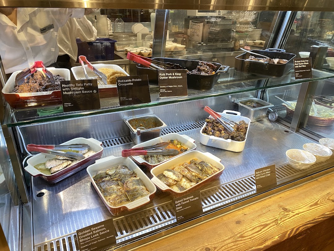 A vibrant display of freshly prepared hot dishes, including healthy options and Japanese-inspired cuisine, at CafèMeal.