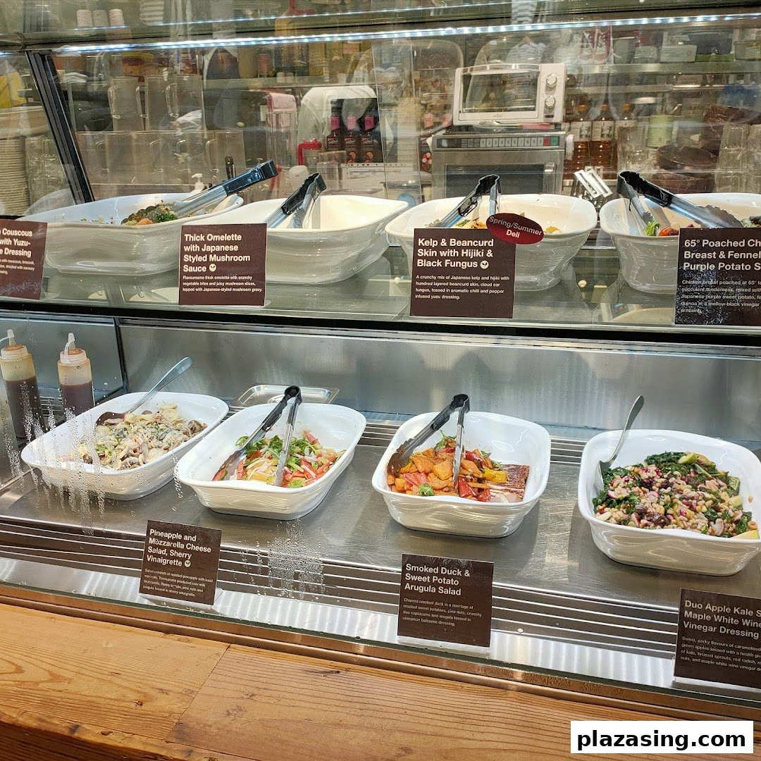 A vibrant display of fresh salads and prepared dishes in a deli counter at CafèMeal.