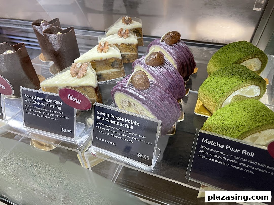 A vibrant display of delicious cakes and pastries, including pumpkin, purple potato, and matcha flavors, with prices.