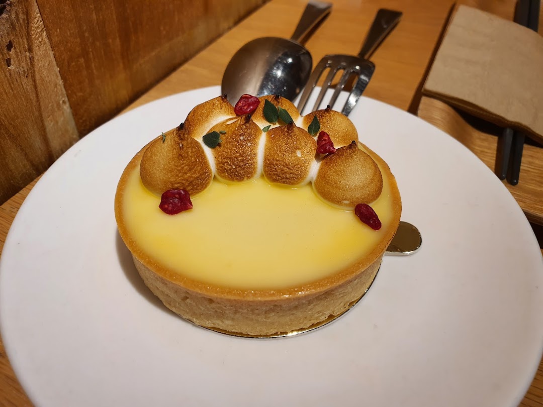 A close-up of a delicious lemon meringue tart with toasted meringue peaks and red berry garnish.