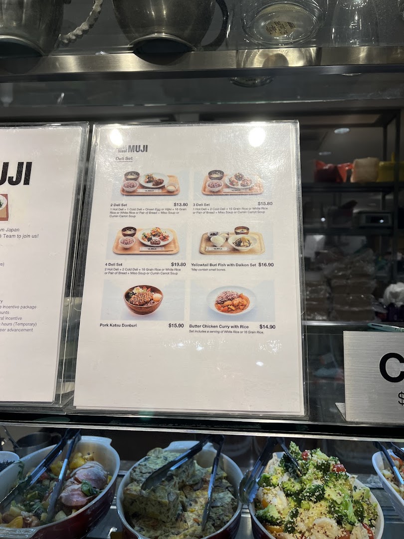 A menu board displaying various deli sets and main dishes with prices at CafèMeal MUJI.
