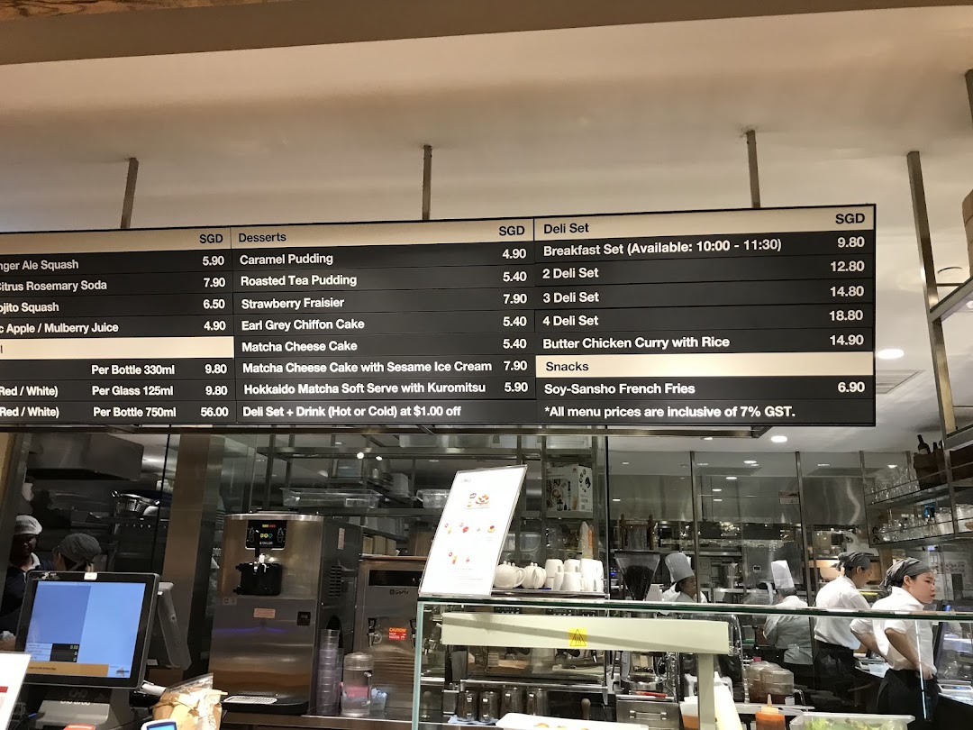 A digital menu board displaying various food and drink options with prices at CafèMeal, with the cafe interior visible.