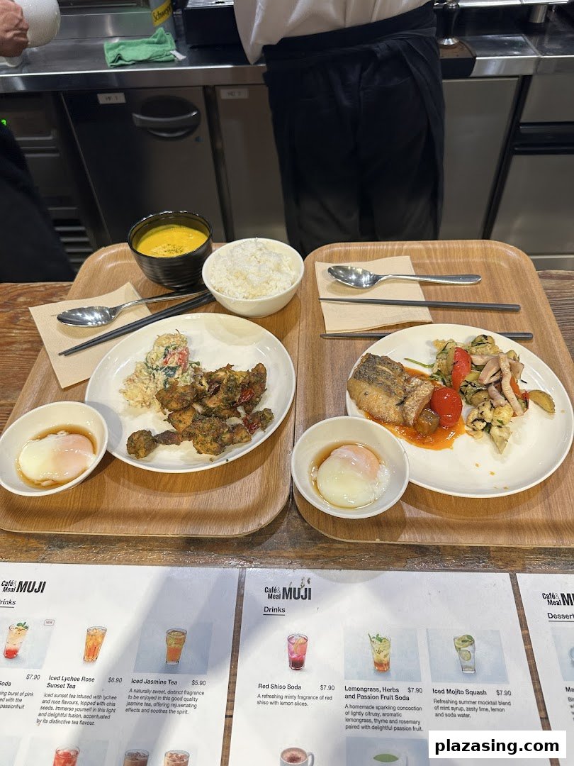 Two wholesome meal trays with various dishes, including rice, soup, and main courses, in a cafe setting with a partial menu visible.