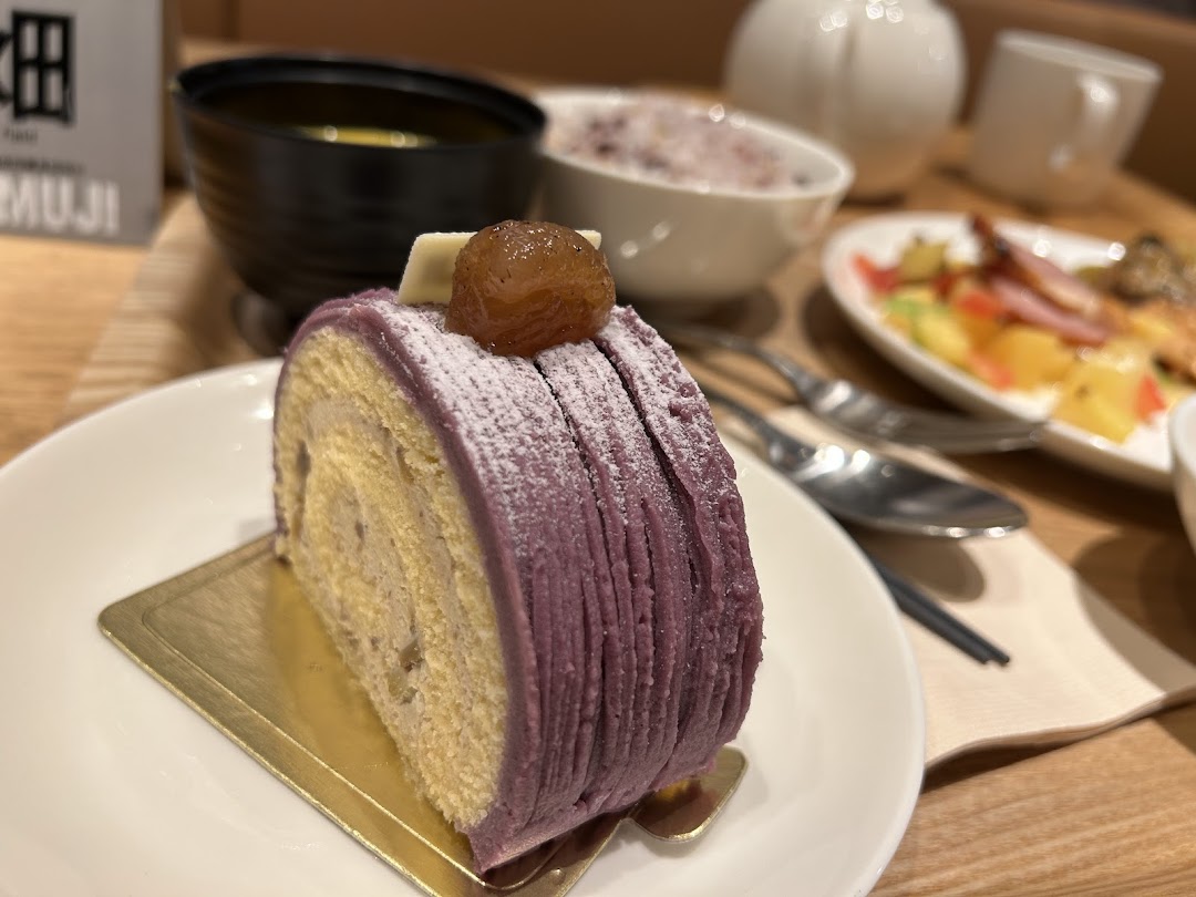A delicious purple roll cake with chestnut topping, served on a white plate in a cozy cafe setting.