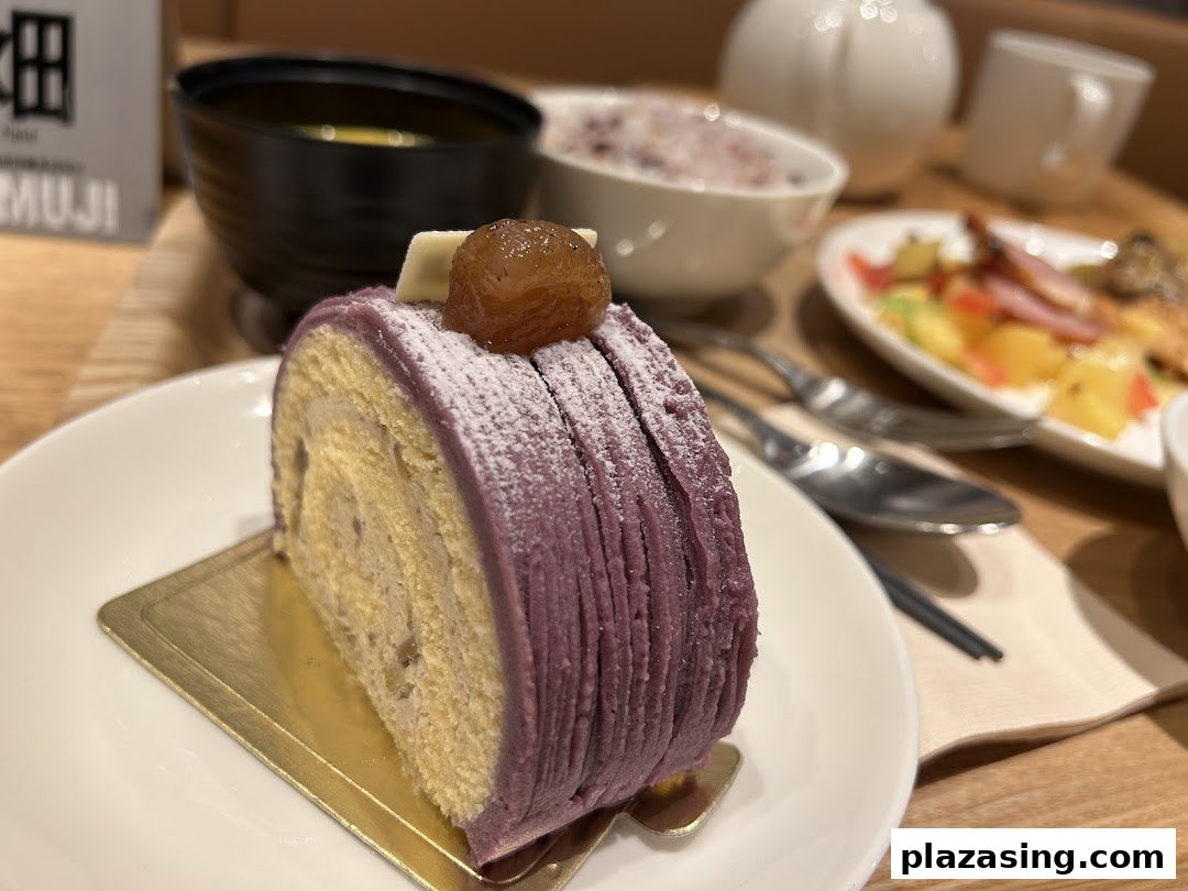 A delicious purple roll cake with chestnut topping, served on a white plate in a cozy cafe setting.