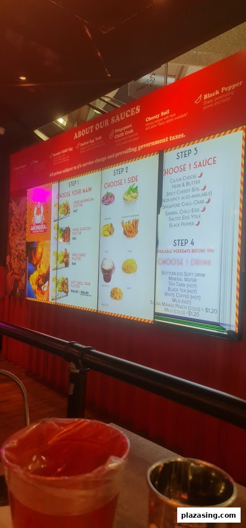 A digital menu board displaying customizable seafood platters, sauces, sides, and drinks.