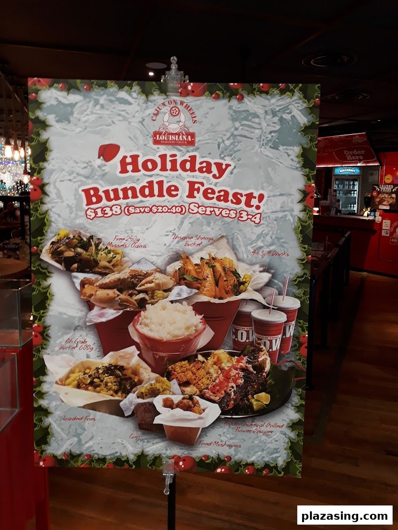 A promotional standee for Cajun on Wheels' 'Holiday Bundle Feast' featuring various seafood dishes.