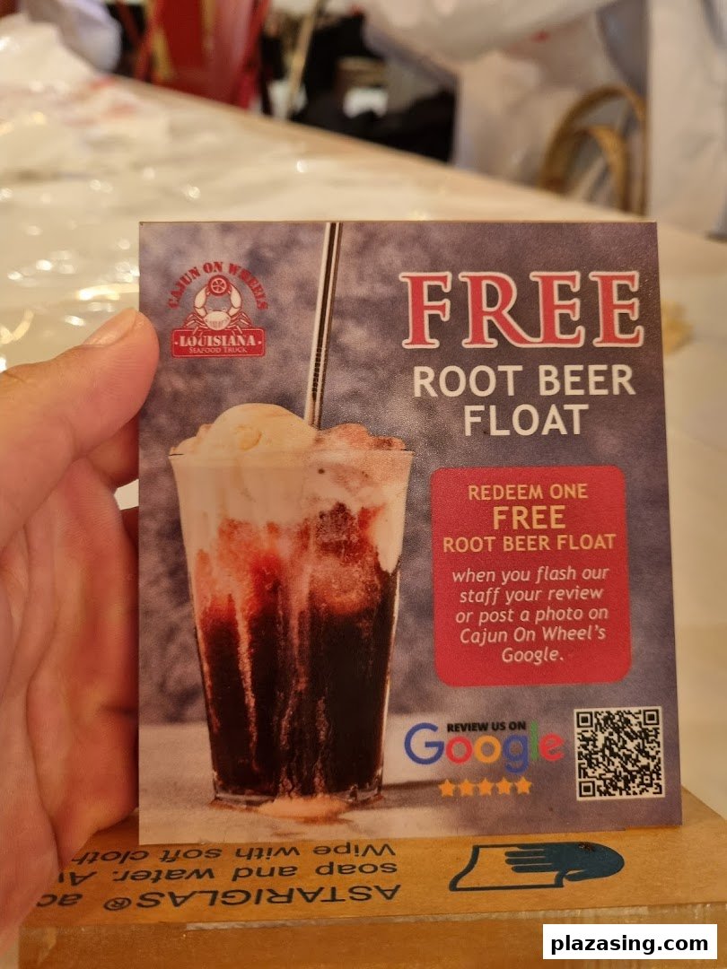 A hand holds a promotional card for Cajun on Wheels offering a free root beer float.