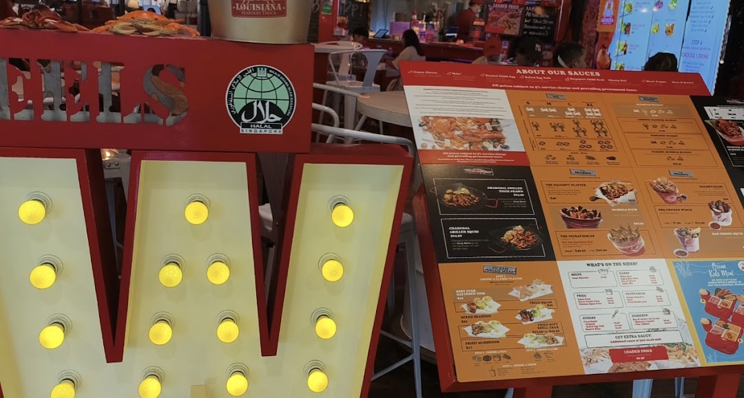A vibrant menu board showcasing Cajun seafood dishes and sides, next to a lighted 'W' sign.