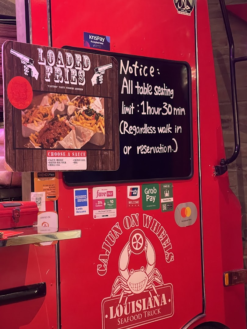 A red food truck, Cajun on Wheels, featuring loaded fries and a seating notice.