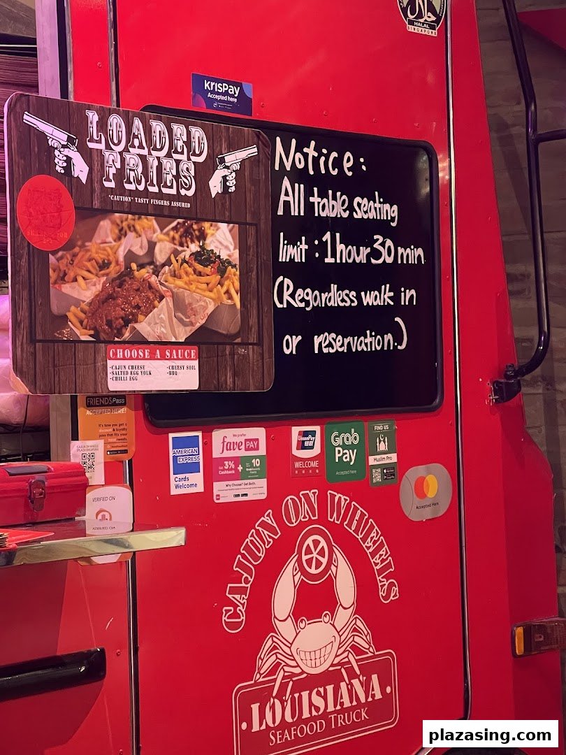 A red food truck, Cajun on Wheels, featuring loaded fries and a seating notice.