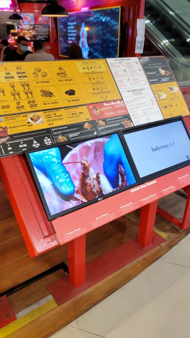 A vibrant display stand showcasing Cajun on Wheels' seafood menu, prices, and sauce options.