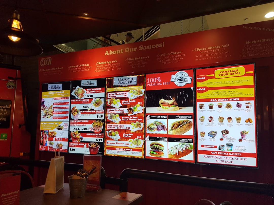 A vibrant digital menu board showcasing Cajun on Wheels' seafood buckets, platters, burgers, and sides.