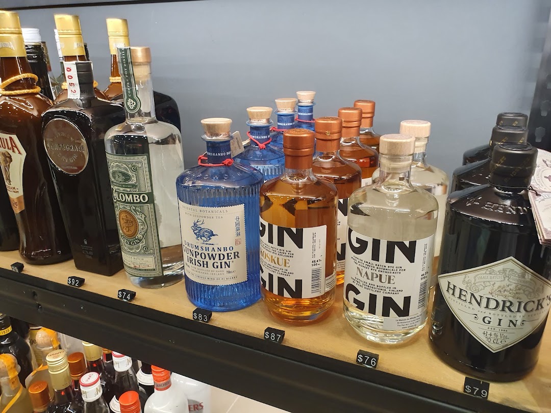 A shelf displaying a variety of premium gin bottles, including Hendrick's, with visible price tags.