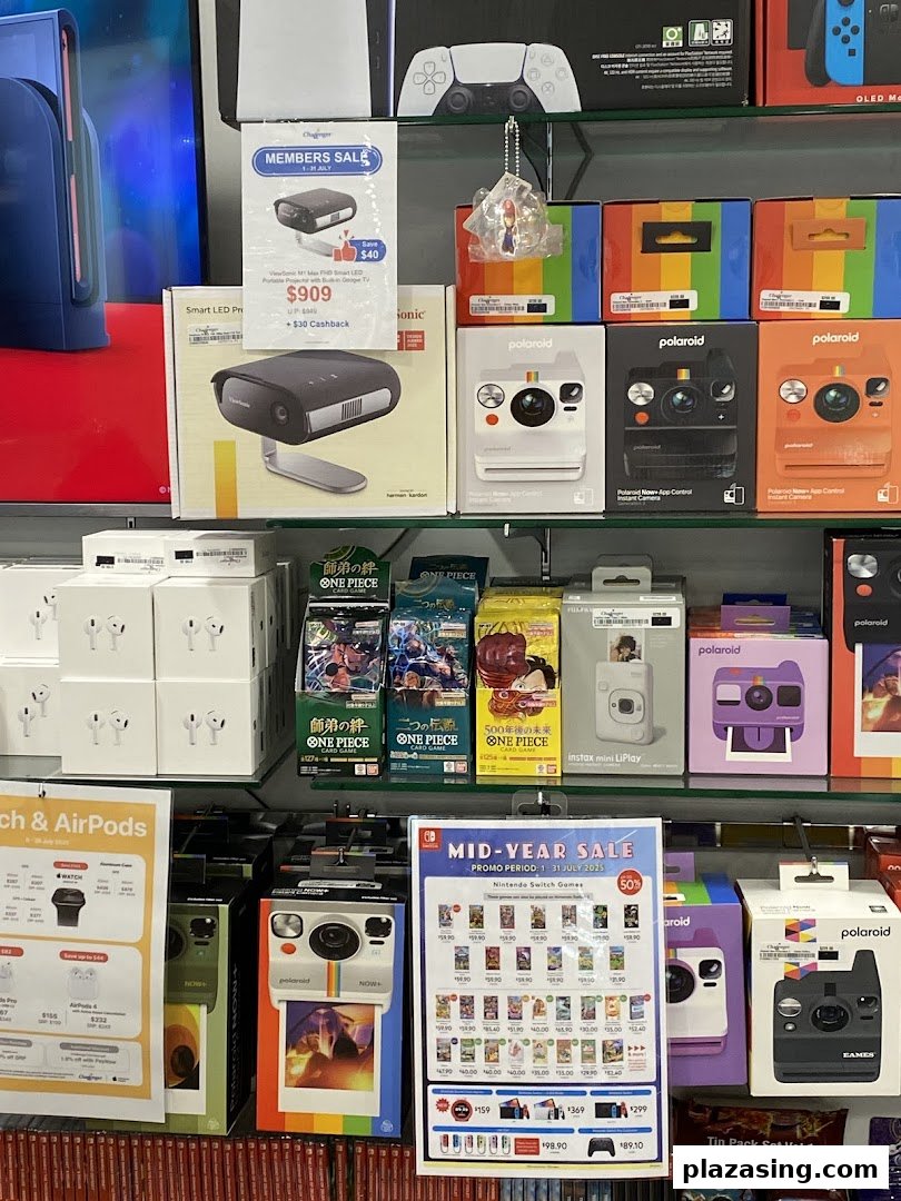 A vibrant display of electronics, including cameras, projectors, and gaming products, on shelves at Challenger.