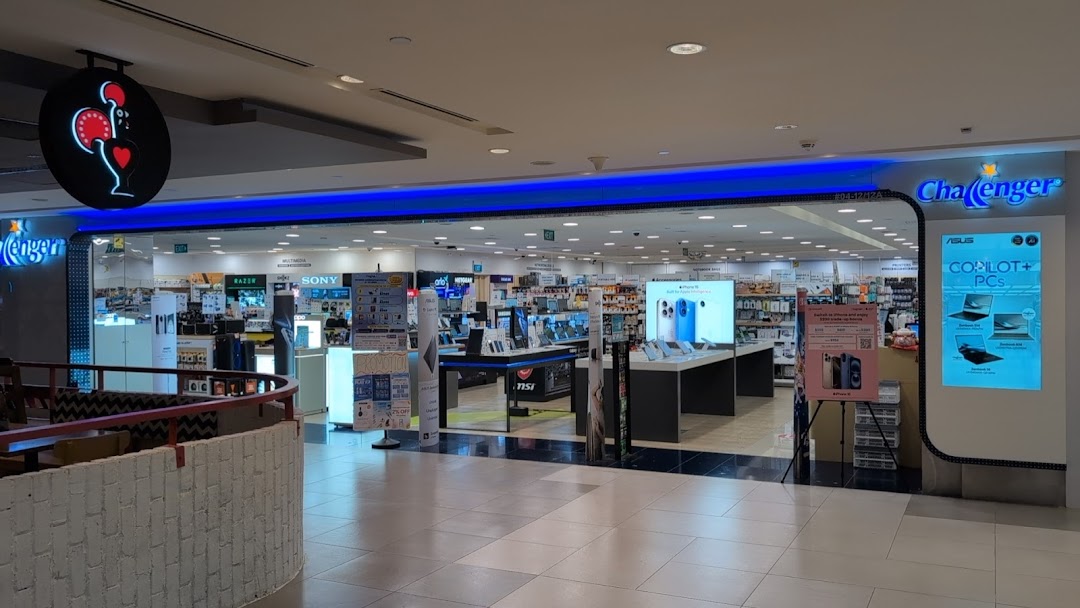 The brightly lit entrance of Challenger, an electronics and IT retail store, showcasing various tech products.