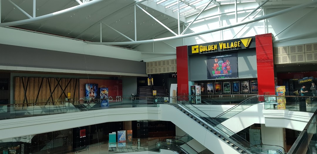 Interior view of a multi-level shopping mall featuring escalators and a Golden Village cinema entrance.