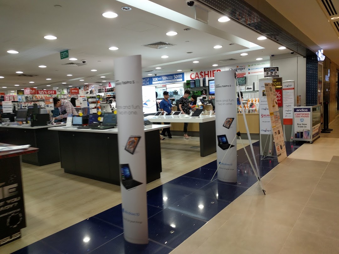 Interior view of Challenger electronics store with customers browsing laptops and various tech products.