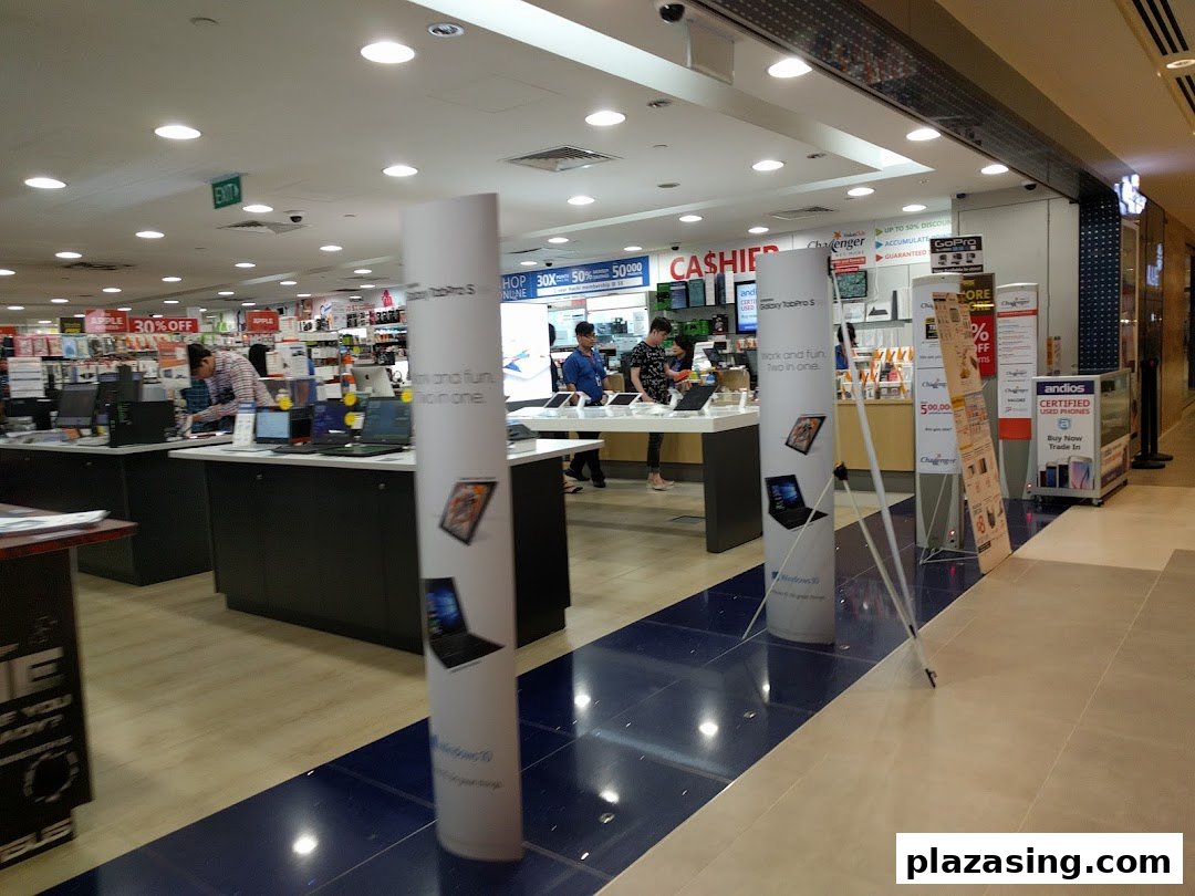 Interior view of Challenger electronics store with customers browsing laptops and various tech products.