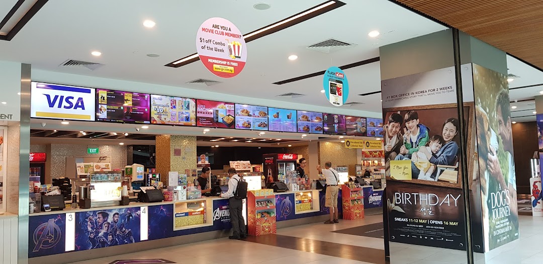 A bustling cinema concession stand with digital menu boards, offering snacks and drinks to moviegoers.