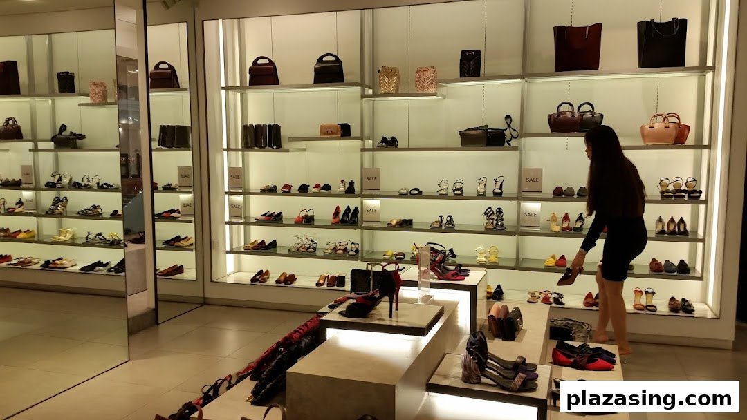 Interior of CHARLES & KEITH store displaying shoes and handbags on illuminated shelves, with a customer browsing.
