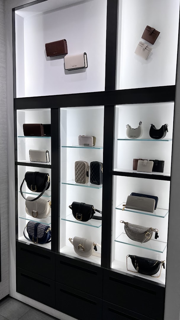 A modern display cabinet showcasing a variety of stylish handbags, wallets, and accessories in neutral tones.