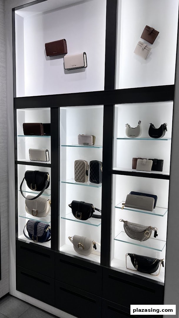 A modern display cabinet showcasing a variety of stylish handbags, wallets, and accessories in neutral tones.