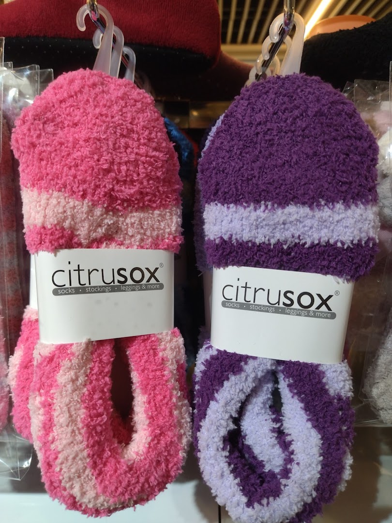 Close-up of two pairs of fluffy, striped Citrusox socks in pink and purple, displayed for sale.