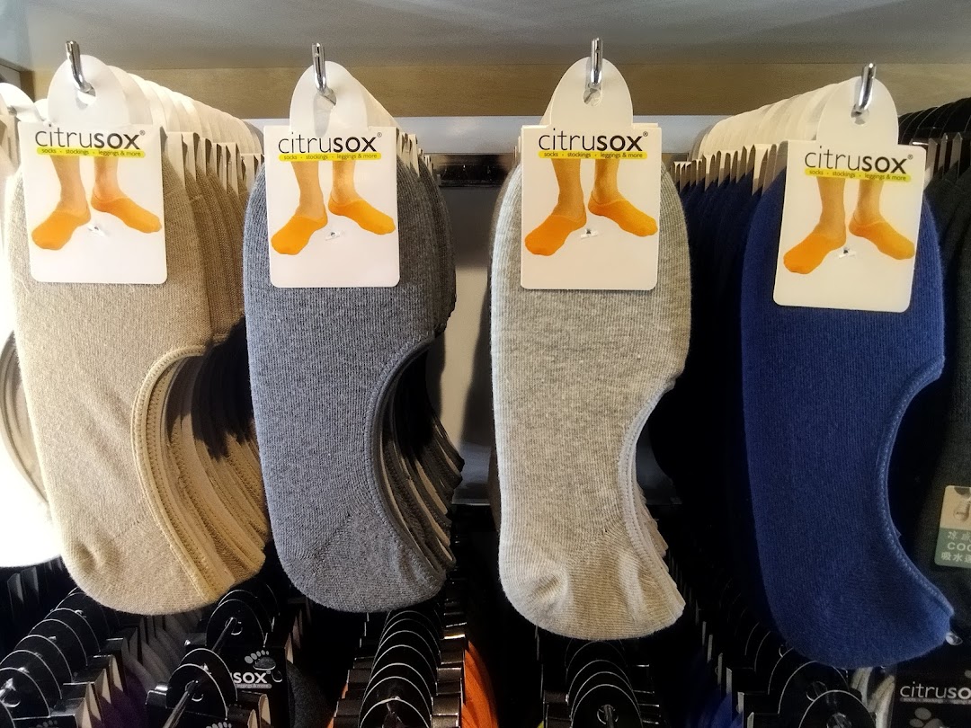 Close-up view of various colored no-show socks from Citrusox displayed on hangers in a retail store.