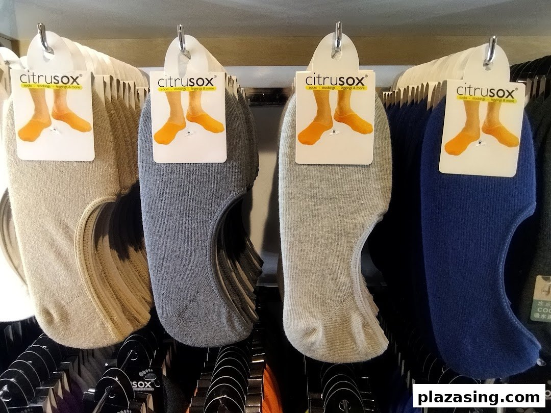 Close-up view of various colored no-show socks from Citrusox displayed on hangers in a retail store.