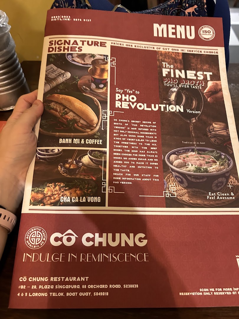 A hand holds a menu for Co Chung Vietnamese Restaurant, showcasing signature dishes and their special Pho.