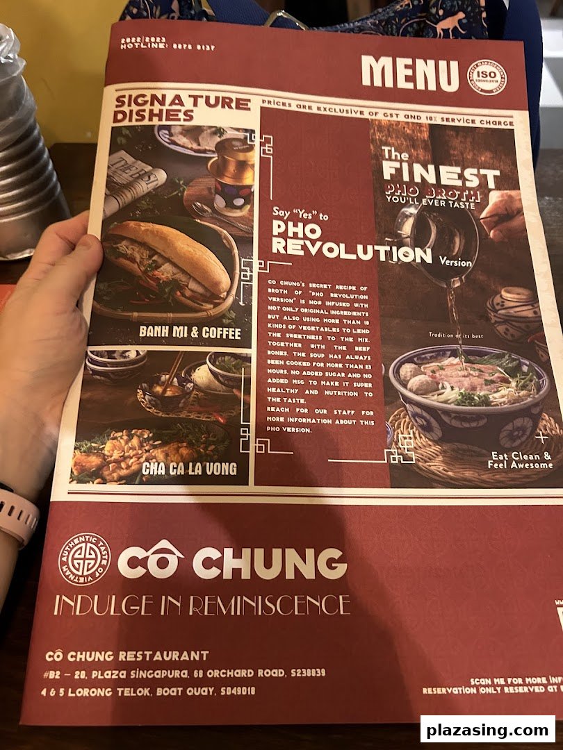 A hand holds a menu for Co Chung Vietnamese Restaurant, showcasing signature dishes and their special Pho.