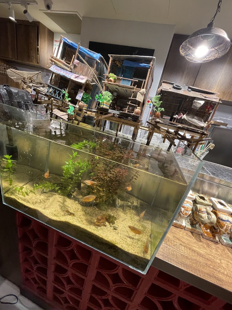 An aquarium with fish and intricate miniature Vietnamese village models, enhancing the restaurant's ambiance.
