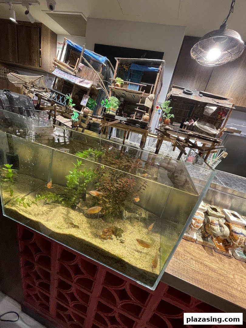 An aquarium with fish and intricate miniature Vietnamese village models, enhancing the restaurant's ambiance.