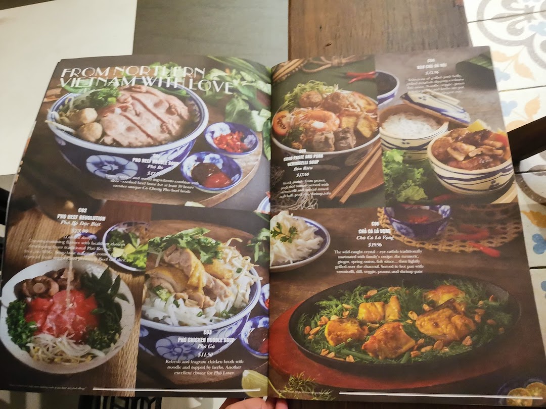 An open menu displaying various Vietnamese noodle soups and main dishes with descriptions and prices.