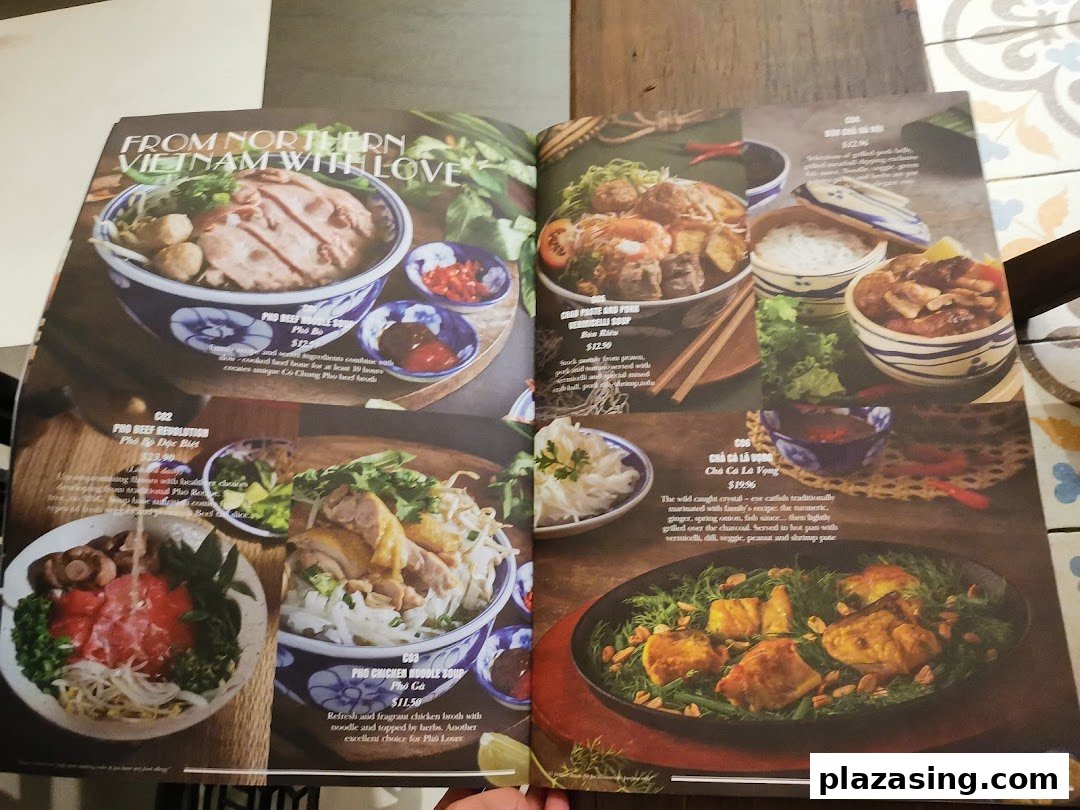 An open menu displaying various Vietnamese noodle soups and main dishes with descriptions and prices.